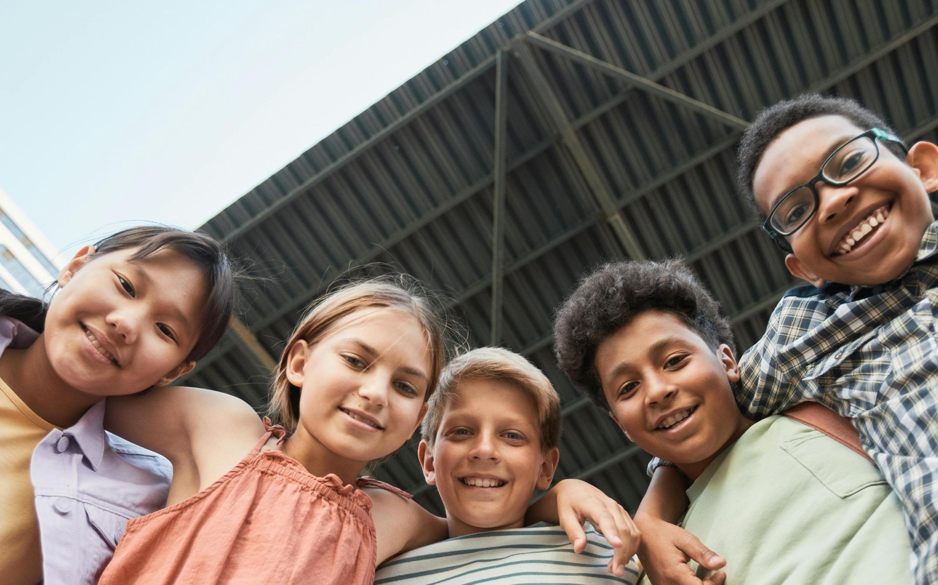 Joyful multicultural group of children smiling and embracing, showcasing friendship and diversity.