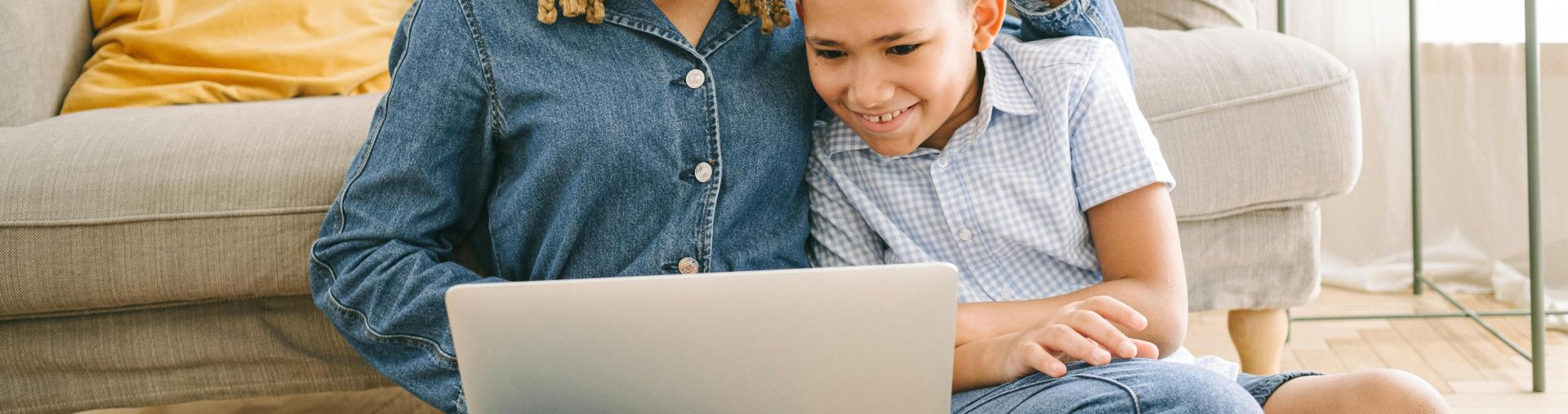 A loving mother and her son enjoying a fun time together while using a laptop indoors.