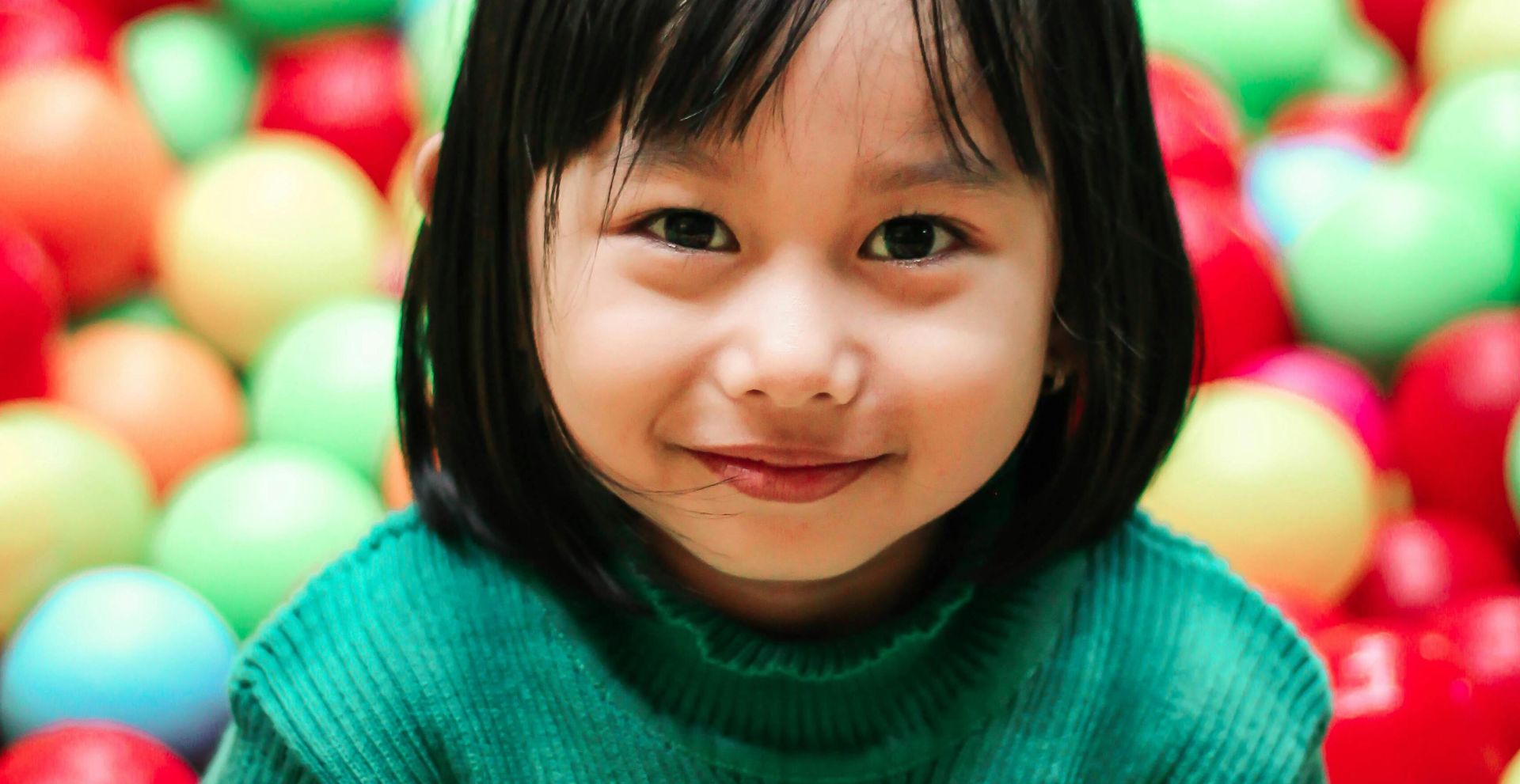 Adorable girl enjoying playtime in a vibrant indoor ball pit.